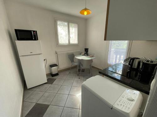 une cuisine avec un réfrigérateur blanc et une table dans l'établissement Le Cocon Annécien, à Annecy