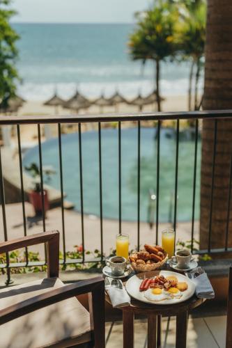 a table with a plate of food with a view of the beach at Tamarina Golf & Spa Boutique Hotel in Flic-en-Flac