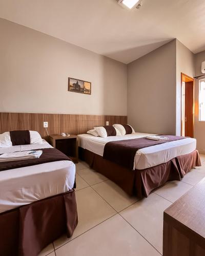 a hotel room with two beds in a room at Hotel Caminhos da Serra in Três Coroas