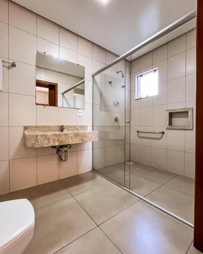 a bathroom with a glass shower and a sink at Hotel Caminhos da Serra in Três Coroas