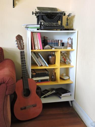 a guitar sitting on a shelf next to a bookcase at Pousada D'amoras in Conservatória