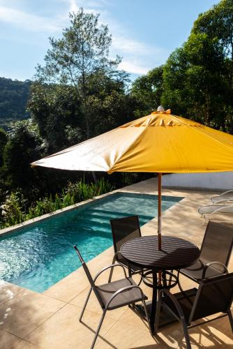 a table with a yellow umbrella next to a swimming pool at Meu Limão Meu Limoeiro in Visconde De Maua