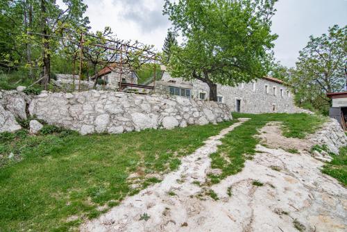 an old stone wall in front of a building at Arija Stone House - Rural Studio Apartment in Nikšić