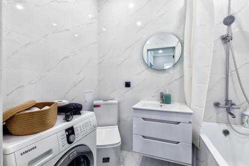 een witte badkamer met een wasmachine en een spiegel bij Комфортные апартаменты в центре города in Astana