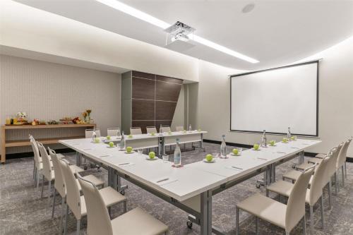 a conference room with a long table and chairs and a screen at NH Collection Monterrey San Pedro in Monterrey