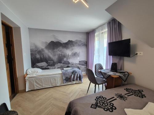 a hotel room with two beds and a desk and a television at Spanie po Zbóju in Kościelisko