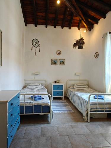 two beds in a bedroom with blue cabinets at Louloudi, charming townhouse in Skiathos