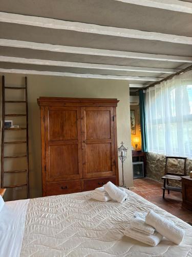 a bedroom with a white bed with a wooden cabinet at CASA VASARI Holiday Suites TUSCANY in Lucignano
