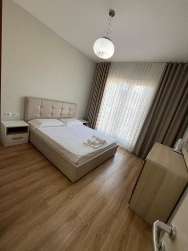 a bedroom with a bed and a large window at Liqeni New Apartament in Tirana