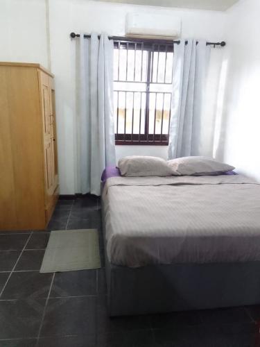 a bedroom with a bed and a window with curtains at House in the center of Paramaribo in Paramaribo