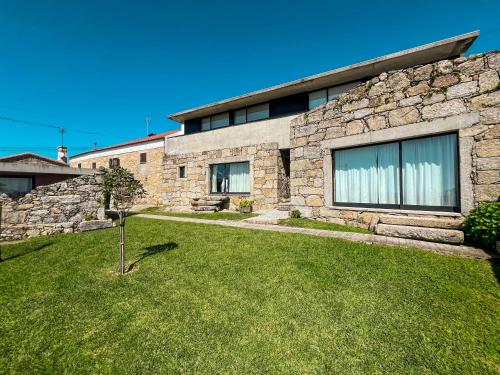 a stone house with a green lawn in front of it at Casas da Fonte in Viana do Castelo