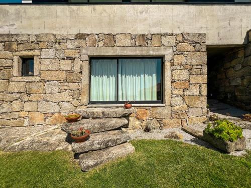 a stone wall with a window and some plants at Casas da Fonte in Viana do Castelo
