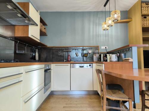 une cuisine avec des armoires blanches et une table en bois dans l'établissement Maison de ville climatisée, 5minutes centre historique, à Avignon