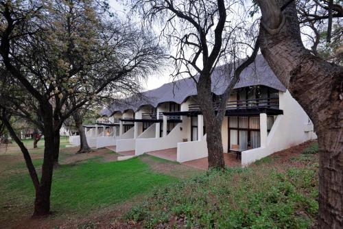 a white building with a black roof and some trees at Kwa Maritane Lodge in Ledig