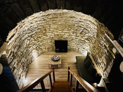 a room with a stone wall with a couch and a table at Charme unique sous les remparts in Châteauneuf-de-Gadagne