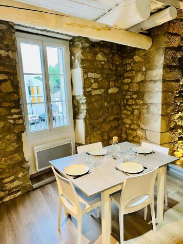 une table et des chaises dans une pièce avec un mur en pierre dans l'établissement Charme unique sous les remparts, à Châteauneuf-de-Gadagne