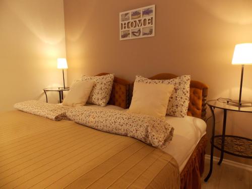 a bedroom with a bed with pillows and two lamps at Éden Villa Apartmanház in Balatonfüred