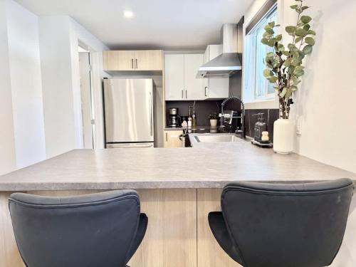 a kitchen with two black chairs at a counter at Le Luxueux 2 in Quebec City