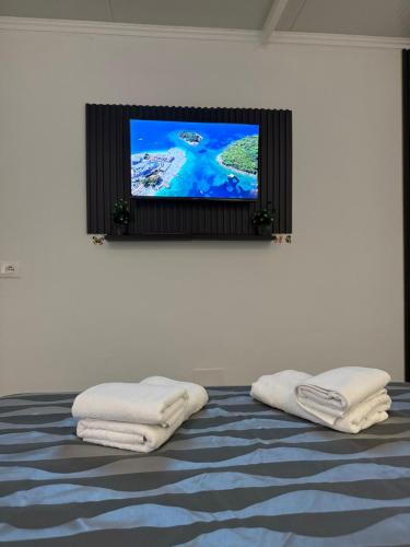a flat screen tv above a bed with two white towels at Mayfair Apartment Ksamil in Ksamil