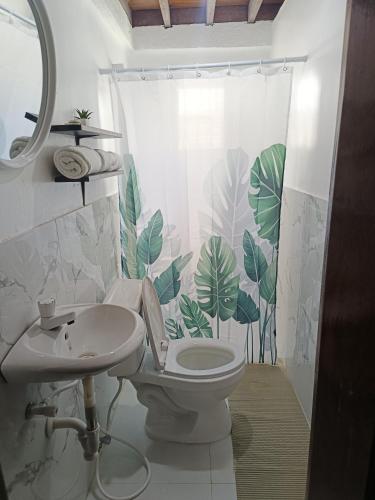 a bathroom with a toilet and a shower curtain with leaves at Bucana Beach House North El Nido in El Nido