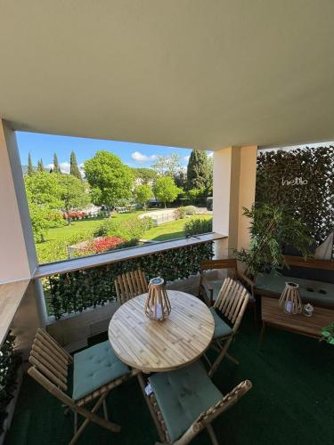 une terrasse avec une table et des chaises ainsi qu'une grande fenêtre. dans l'établissement Appartement 211 - LES SUITES DE ROBINSON - Résidence avec piscine en bord de Siagne, à Mandelieu-La-Napoule, à Mandelieu-la-Napoule