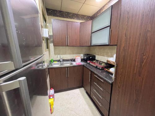 アジュマーンにあるDuplex Two BHKのキッチン(木製キャビネット、ステンレス製の冷蔵庫付)