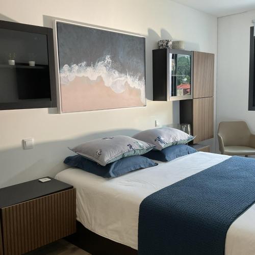 a bedroom with a bed with blue pillows and a tv at Luxury Villa with Pool & Sea View-10 Minutes from Monaco in Èze