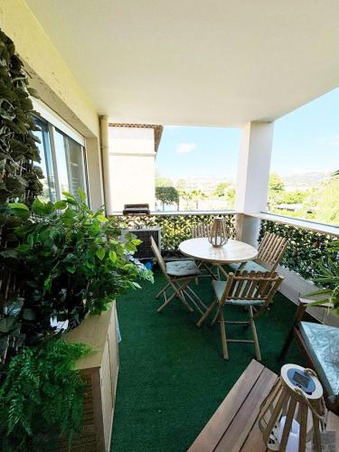 un patio avec une table et des chaises sur un balcon dans l'établissement Appartement 211 - LES SUITES DE ROBINSON - Résidence avec piscine en bord de Siagne, à Mandelieu-La-Napoule, à Mandelieu-la-Napoule