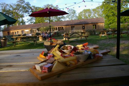 un plateau de nourriture sur une table en bois avec un parasol dans l'établissement Hôtel et Cottages Domaine Du Marquenterre, à Saint-Quentin-en-Tourmont