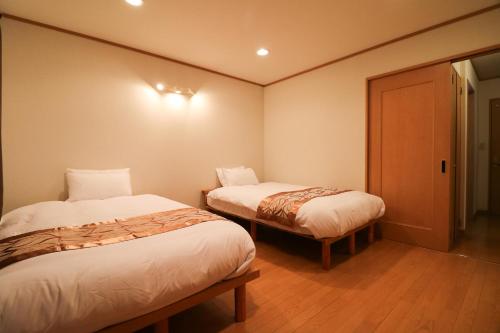 a small room with two beds and a door at Relax House Misato in Shiraoi