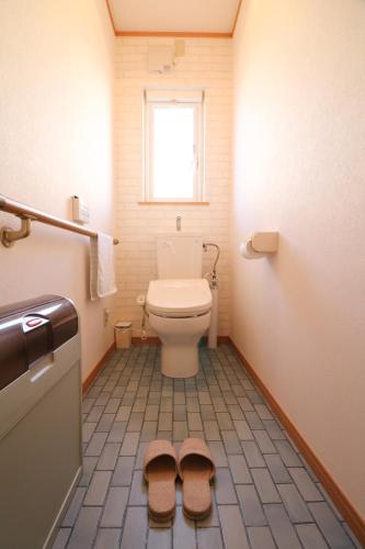 a bathroom with a toilet with two slippers on the floor at Relax House Misato in Shiraoi