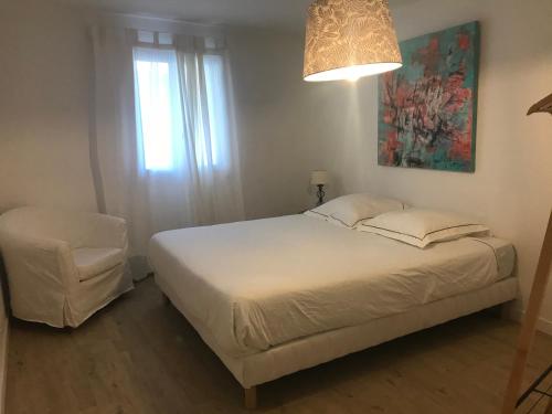 une chambre avec un lit blanc et une chaise dans l'établissement Il y a le Soleil, la Campagne et la Mer …1, à Martigues