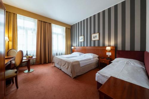 a hotel room with two beds and a desk at Hotel Raffaello Prague in Prague