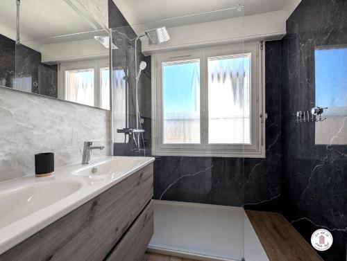 La salle de bains est pourvue d'un lavabo, d'une baignoire et d'une fenêtre. dans l'établissement Villa Petros, à Les Sables-dʼOlonne