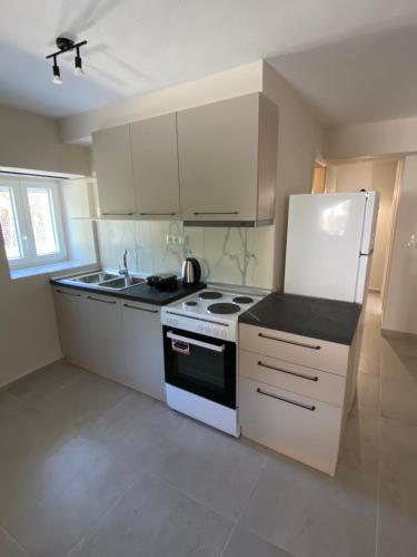 a kitchen with white cabinets and a stove and refrigerator at Alion houses in Prinos