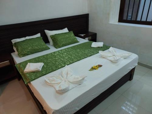 a bed with green and white sheets and flowers on it at Das Haus Villa & Restaurant in Unawatuna