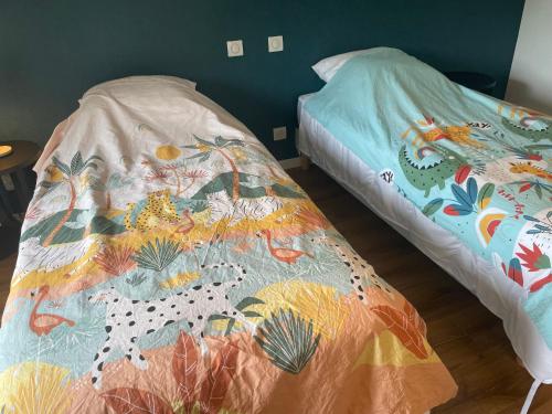 a bed with a comforter on it next to a bedskirts at Gîte spacieux et calme proche de La Flèche, idéal pour familles - FR-1-410-470 in Villaines-sous-Malicorne