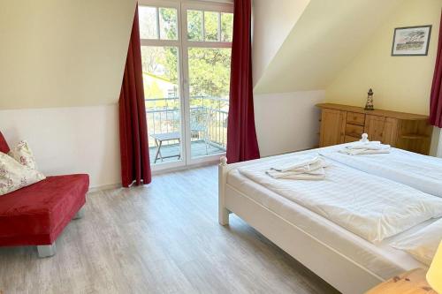 a bedroom with a white bed and a red chair at Holiday-2 in Prerow