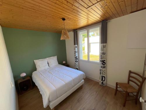 une chambre avec un lit blanc et une fenêtre dans l'établissement Maison de famille à 300m de la plage, à Saint-Jean-de-Monts