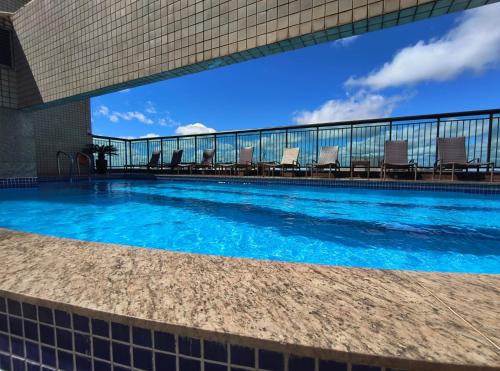 巴西利亚Flat particular no Hotel Grand Mercure com varanda, garagem e wi-fi的一座建筑物边带椅子的游泳池