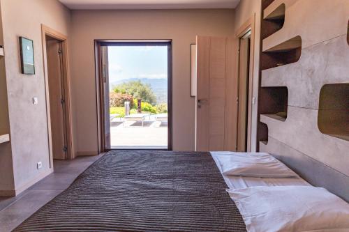 - une chambre avec un lit et une grande porte en verre dans l'établissement Villa Paolina, à Sainte-Lucie de Porto-Vecchio