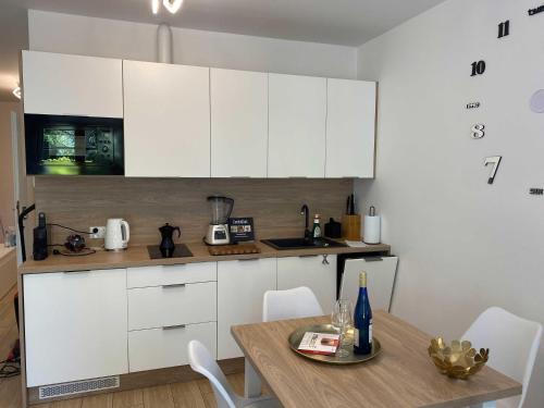 a kitchen with white cabinets and a wooden table at eMeN Apartamenty Jastarnia in Jastarnia