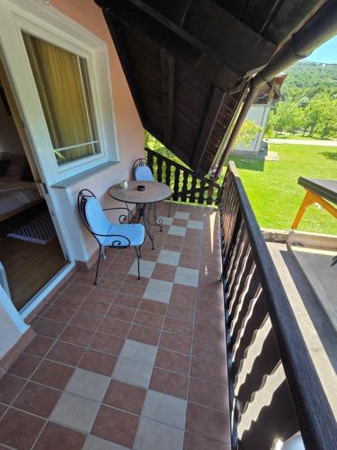 a balcony with a table and chairs on a house at Apartman & Sobe Orhideja in Smoljanac