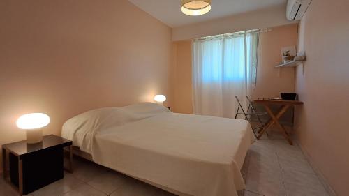 - une chambre avec un lit blanc et deux lampes dans l'établissement T3 Les Juandines, à Antibes