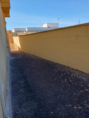 an empty parking lot next to a yellow wall at Casa sole e luna in Porto Cesareo