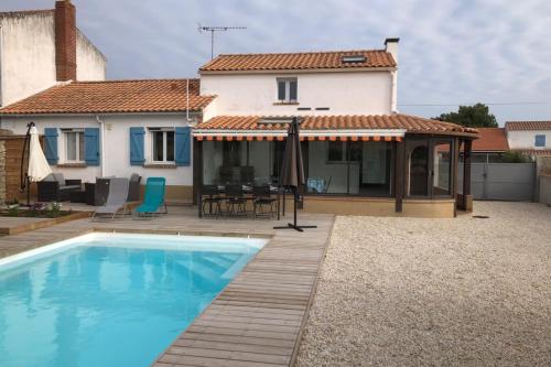 a villa with a swimming pool in front of a house at Maison avec piscine privée chauffée in La Guérinière
