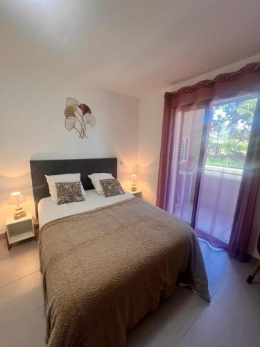 une chambre avec un grand lit et une grande fenêtre dans l'établissement Appartement A Maghjina proche port et centre ville, à Porto-Vecchio