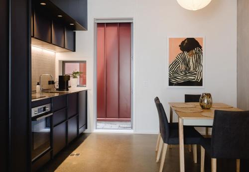 a kitchen and dining room with a table and a red door at NYC Loft Vibe! 2BR City Stay w Rooftop Terrace in Wellington
