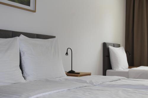 a bedroom with a bed with white sheets and a lamp at Apartmány Abacie in Nový Jičín