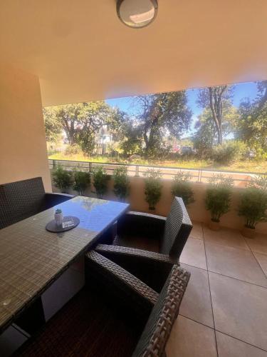 une terrasse avec une table et des chaises ainsi qu'une grande fenêtre. dans l'établissement Appartement A Maghjina proche port et centre ville, à Porto-Vecchio